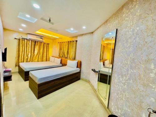 a hotel room with two beds and a mirror at Hotel Diamond inn-Esplanade in Kolkata