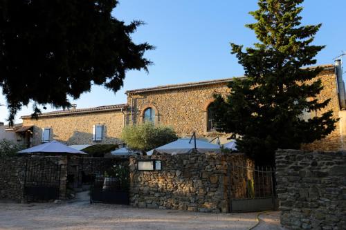 a stone fence with umbrellas in front of a building at Logis Hôtel Château De Palaja in Carcassonne