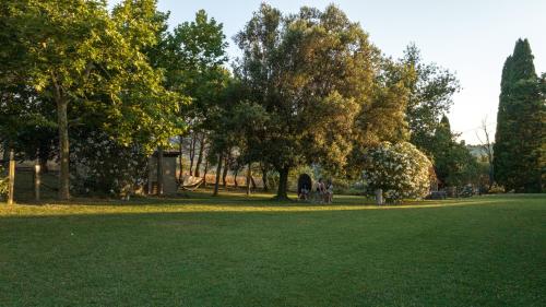 a park with trees and people standing in the grass at Agriturismo San Carlo in Pomarance