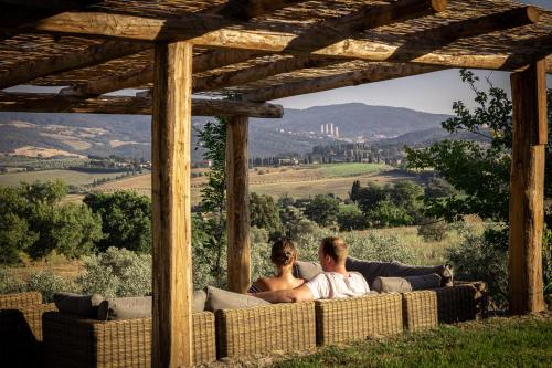 a man and woman sitting on a couch under a pergola at Agriturismo San Carlo in Pomarance