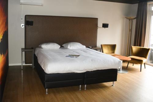 a bedroom with a large bed and two chairs at Fletcher Hotel-Restaurant de Korenbeurs in Made