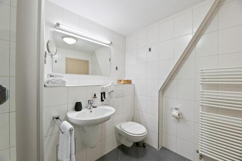 a white bathroom with a toilet and a sink at Steiners Hotel Airport-Messe in Birkach in Stuttgart