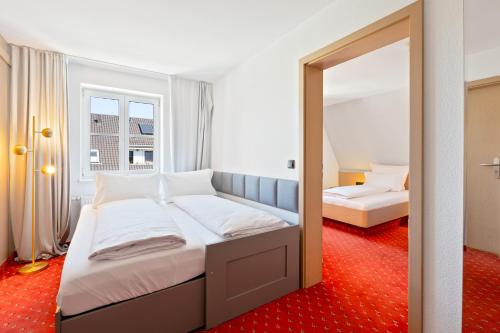 a bedroom with two beds and a mirror at Steiners Hotel Airport-Messe in Birkach in Stuttgart