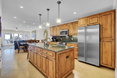 Una cocina con gabinetes de madera y un refrigerador de acero inoxidable. en Beach Club Villa 12 by Wild Dunes, Oceanfront Condo, en Isle of Palms