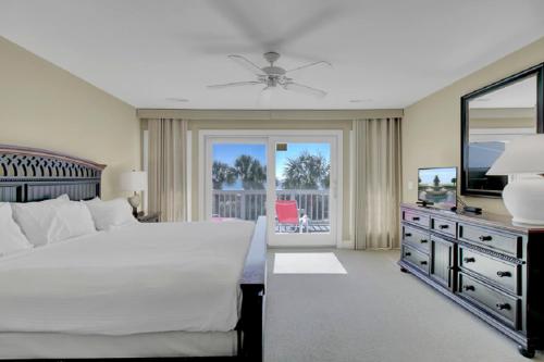 a bedroom with a bed and a television and a balcony at Beach Club Villa 12 by Wild Dunes, Oceanfront Condo in Isle of Palms