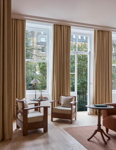a living room with chairs and tables and windows at Miiro Templeton Garden in London