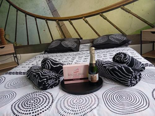 - une bouteille de champagne sur un lit avec des oreillers noirs et blancs dans l'établissement la loge sparnacienne, à Épernay