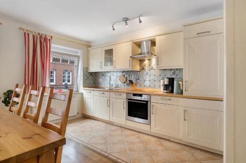 a kitchen with white cabinets and a table and chairs at Apartment Altstadtflair in Husum