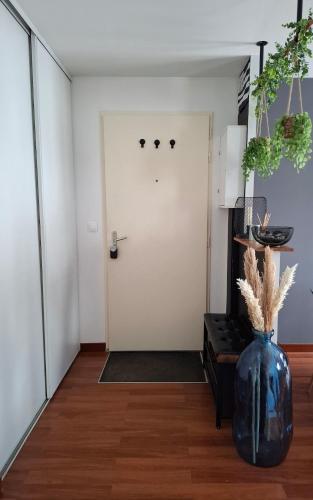 un couloir avec une porte blanche et un vase bleu dans l'établissement Appartement Cosy Chartres-de-Bretagne, à Chartres-de-Bretagne