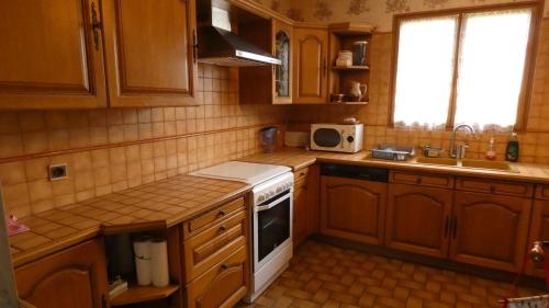 une cuisine avec des armoires en bois et un four blanc dans l'établissement L'Evasion, maison spacieuse, véranda, parking, à Saint-André-de-Cubzac