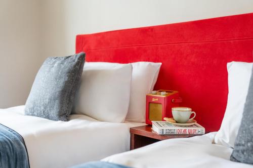 a bed with a red headboard and a cup on a table at The Clifton Hotel Bristol in Bristol