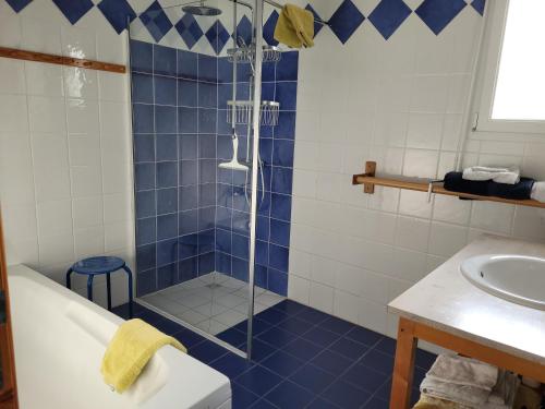 La salle de bains est pourvue de carrelage bleu, d'une douche et d'un lavabo. dans l'établissement La Mouette, à Plozévet