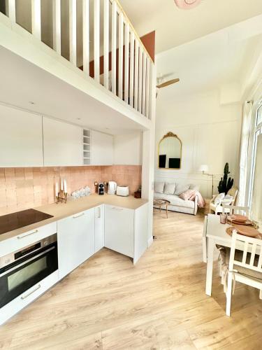 une cuisine avec des armoires blanches et un salon dans l'établissement Winter Palace - Parking - Centre - Calme, à Menton