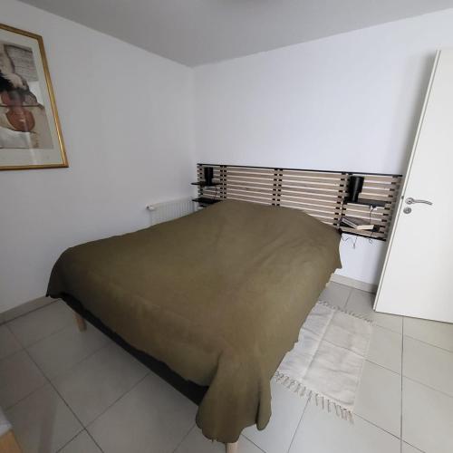 Ce lit se trouve dans un dortoir blanc doté d'une couverture verte. dans l'établissement Appartement du port, à Sète