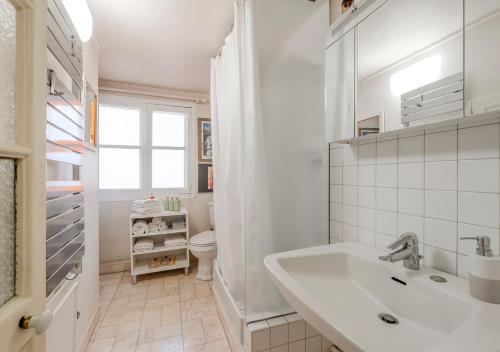 une salle de bain blanche avec un lavabo et des toilettes dans l'établissement La Pause Parisienne, au pied du métro, à Paris