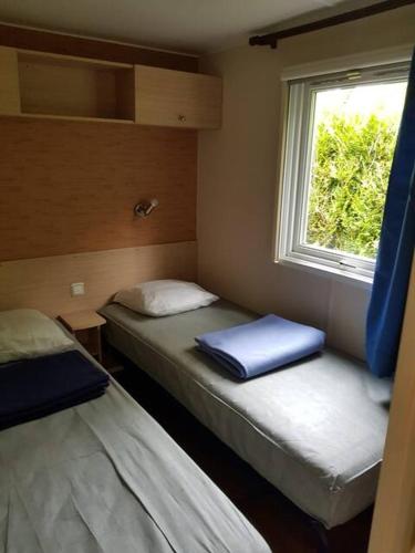 deux lits dans une petite pièce avec une fenêtre dans l'établissement Cabane du bonheur, à Saint-Chéron