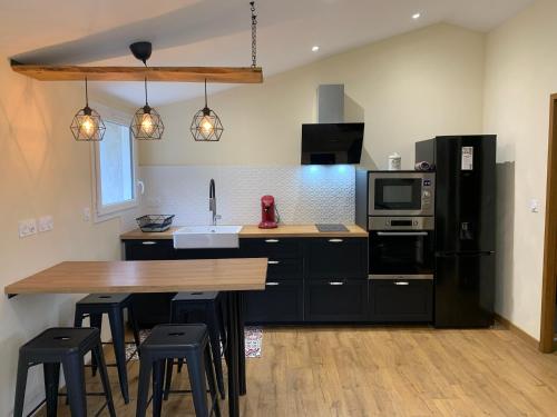a kitchen with black cabinets and a wooden table with stools at La Loubière - le gîte au cœur de la nature in Combret