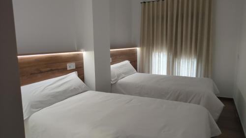 a hotel room with two beds and a window at Kalea Elysivm in Alcalá del Júcar