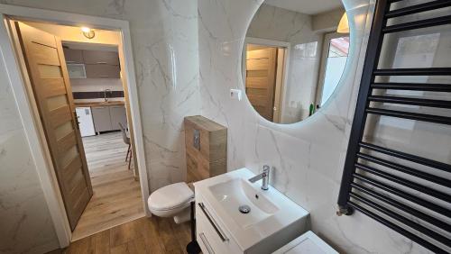 a white bathroom with a sink and a mirror at Apartament przy Sosnowej in Lublin