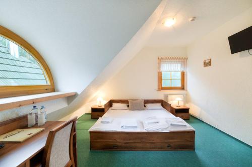 a bedroom with a bed and a desk and a window at Jakubowa Izba in Niwa Babicka