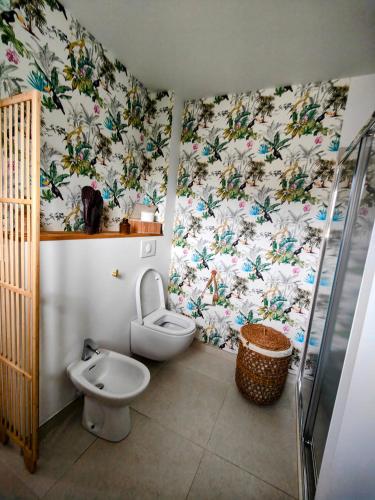 La salle de bains est pourvue de toilettes et d'une douche avec du papier peint floral. dans l'établissement La Grande Molinie, à Le Porge