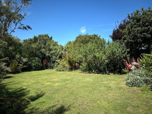 a garden with grass and trees and bushes at Comme un petit coin de paradis à Trégastel in Trégastel