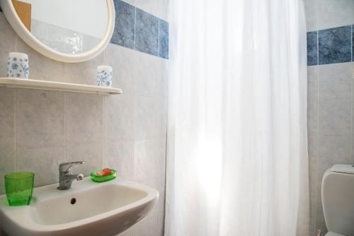 a bathroom with a sink and a white shower curtain at Yiannis Yard studios & apartments in Kos Town