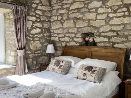 a bedroom with a bed and a stone wall at Ryedale Cottage in Helmsley