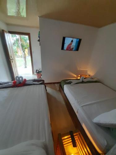 two beds in a room with a tv on the wall at Cabañas la Miranda in Filandia