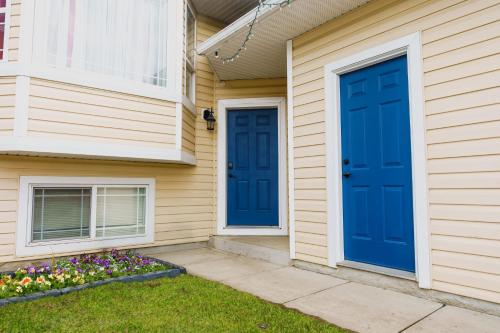 two blue doors on the side of a house with flowers at entire house THE BLUE DOOR with garage access in Grande Prairie