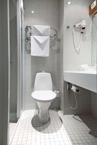 a white bathroom with a toilet and a sink at Scandic Plaza Turku in Turku