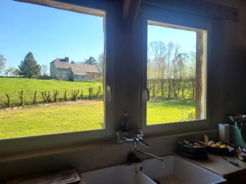 deux fenêtres dans une cuisine avec vue sur un champ dans l'établissement Chaumière Normande, à Pierrefiques