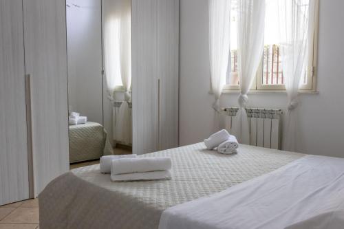 a white bedroom with two towels on a bed at Andrea's Dépendance in Letojanni