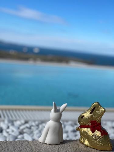 two figurines of a rabbit and a dog sitting on a beach at SunSeaPoolsideStudio CasaSolare VistaMare in Muggia