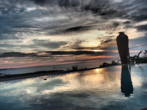a swimming pool with a sunset in the background at SunSeaPoolsideStudio CasaSolare VistaMare in Muggia