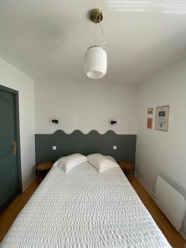 a bedroom with a white bed with a green headboard at Hôtel Les Voisins Beaucemaine in Ploufragan