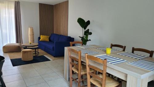 une table à manger avec des chaises et un canapé bleu dans l'établissement La petite maison du Florival, à Guebwiller