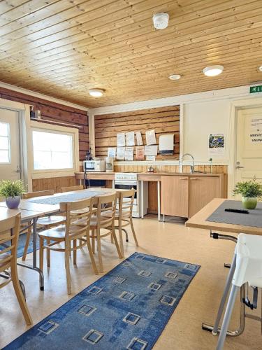 a kitchen with wooden ceilings and tables and chairs at Pohjanranta Cottages in Keminmaa