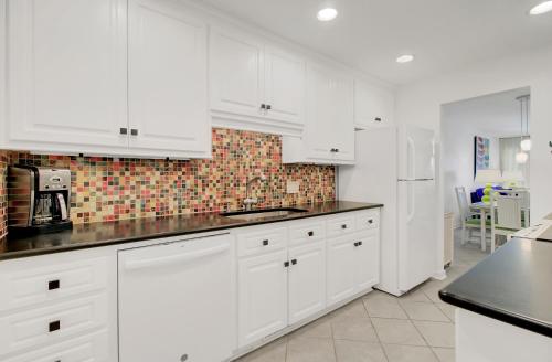 Una cocina con gabinetes blancos y encimeras negras. en Beach Club Villa 53 by Wild Dunes, Oceanfront, en Isle of Palms