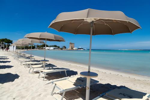 a row of chairs and umbrellas on a beach at Isid'Oro Rooms - 100m from the sea in Sant'Isidoro