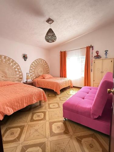 a bedroom with two beds and a purple couch at Casa con Alberca La Mexicana in La Calera