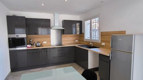 a kitchen with black cabinets and a refrigerator at Maison tout confort belle terrasse sud in Sigean