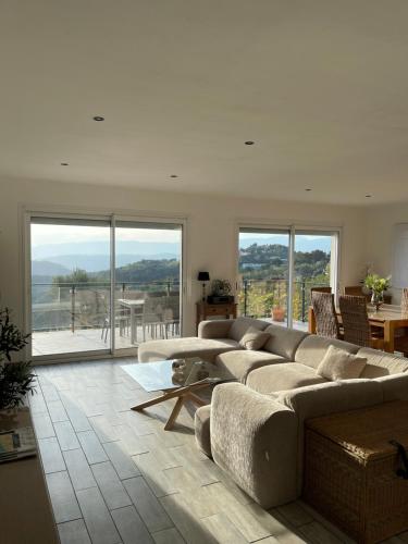 - un salon avec un canapé, une table et des fenêtres dans l'établissement Lou Soulèou Trémoun, à Tanneron