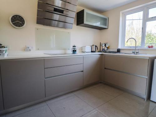 a kitchen with white counters and a sink and a window at Fig Tree House in Axminster