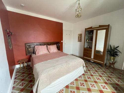 a bedroom with a bed and a red wall at Les volets verts in Saint-Laurent-de-la-Cabrerisse