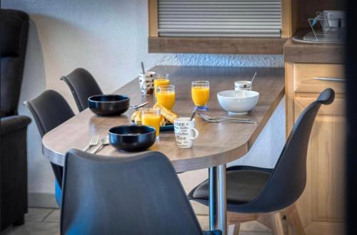 a wooden table with glasses of orange juice on it at Le Giérois - Gare - Parking in Gières