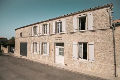 a brick building with white doors on a street at Le Logis de la Gabirotte in Nieulle-sur-Seudre