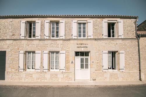 a brick building with a white door on a street at Le Logis de la Gabirotte in Nieulle-sur-Seudre