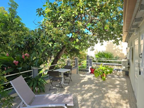 a patio with a table and chairs under a tree at Très Joli T2 à Petit-Bourg in Petit-Bourg