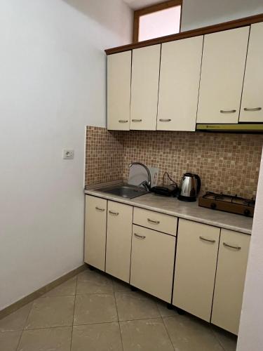 una cucina con mobili bianchi e un lavello di Dario's Apartaments a Orikum